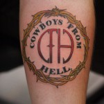 Фото татуировки с логотипом музыкальной группы Pantera 'Cowboys From Hell' на икре. Логотип выполнен в ярких цветах с использованием черного, красного и белого.