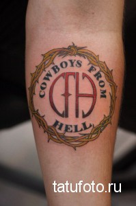 Фото татуировки с логотипом музыкальной группы Pantera 'Cowboys From Hell' на икре. Логотип выполнен в ярких цветах с использованием черного, красного и белого.