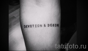 Черно-белое фото татуировки с надписью 'Devotion & Desire' на предплечье. Простой, элегантный шрифт, четкие линии.