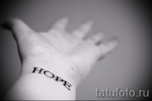 Черно-белое фото татуировки с надписью 'Hope' на запястье. Простой, лаконичный шрифт, четкие линии. Идеально для любителей минимализма.