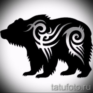 Фотография черно-белой татуировки медведя в стиле трайбл, с использованием геометрических узоров и спиралей.
