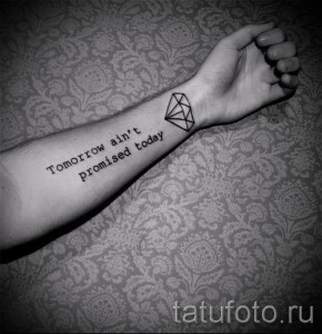 Фото тату: татуировка бриллианта и фразы "Tomorrow ain't promised today" на предплечье.