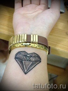 Фото тату на запястье: бриллиант в форме сердца, выполненный в технике blackwork. Четкие линии, минималистичный дизайн.