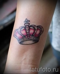 Фото тату на запястье: розовая корона с серебряными контурами и драгоценными камнями. Элегантный рисунок татуировки в нежном стиле.