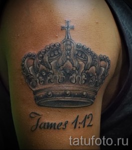Фото тату на плече: большая корона с крестом наверху и надписью 'James 1:12'. Религиозный рисунок татуировки в черном цвете.