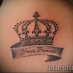 Фото татуировки короны с надписью 'Yours Princess' на спине. Черно-серый рисунок татуировки в стиле графика.
