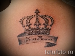 Фото татуировки короны с надписью 'Yours Princess' на спине. Черно-серый рисунок татуировки в стиле графика.