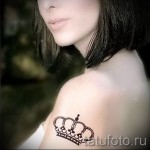 Фото тату на плече: изящная черная корона с детальной проработкой. Женственная татуировка, выполненная в графическом стиле, подчеркивает красоту и грацию.