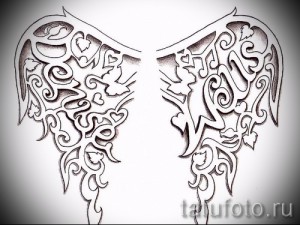 Черно-белый эскиз татуировки, изображающий два крыла, украшенных витиеватыми надписями и узорами, с детальной проработкой элементов.