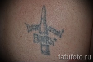 Фотография простой татуировки на плече с изображением самолета и надписью 'Death to Stalin', выполненной в черно-серых тонах.