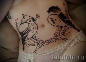 Фото тату: Татуировка на животе, изображающая птиц с ключом в клюве. Оригинальный и символичный дизайн.