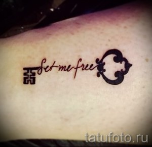 Фото минималистичной татуировки с изображением ключа и надписи "Set me free". Черно-красный рисунок на руке.