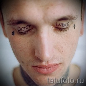 Фотография татуировок надписей "DON'T WAKE" на веках и слезы под глазом мужчины. Экстремальный и провокационный рисунок татуировки.