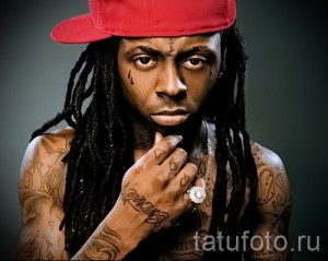 Фото рэпера Lil Wayne с многочисленными татуировками на лице, шее и руках. Эпатажный образ и яркий стиль.