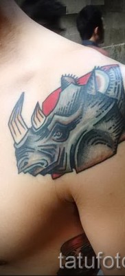 Фото пример тату носорог — цветная тату на передней части плеча парня