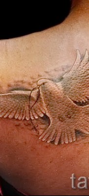Фото тату голубь с ниточкой в клюве — женская татуировка на лопатке