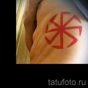 Фото татуировки с красным коловратом на руке. Простой, но символичный рисунок, выполненный четкими линиями. Идеально для поклонников славянской культуры.