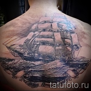 Фото тату на спине: детализированный черно-серый рисунок парусника в бурном море. Под кораблем надпись 'Always Remember'.