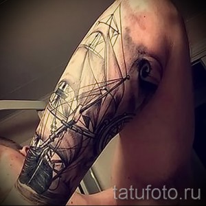 Фото тату парусника на плече. Черно-серый рисунок с высокой степенью детализации, изображающий старинный корабль в море. Реалистичная проработка парусов, мачт и волн.
