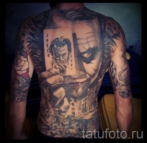 Фото тату Джокера и Бэтмена, покрывающего спину, руки и грудь. Детализированное изображение персонажей и городского пейзажа.