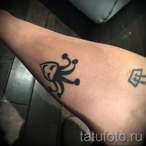 Фотография миниатюрной татуировки Джокера на запястье. Изображена маска и улыбка, выполненные в черном цвете.