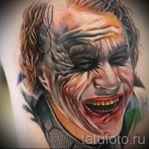 Фотография реалистичной татуировки Джокера на предплечье. Детализированное изображение лица с безумной улыбкой и ярким макияжем.