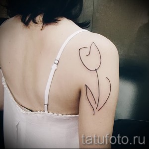 Фото тату тюльпана на плече, выполненного тонкими линиями. Эскиз татуировки в стиле минимализм, подчеркивающий изящество и женственность.