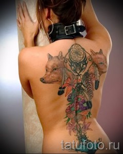 Фото тату на спине с изображением двух лис, цветов и ловца снов. Яркие цвета и детализированная проработка.