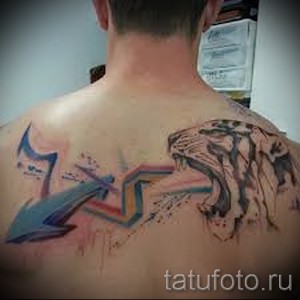 Фото татуировки на спине: реалистичное изображение головы тигра в сочетании с яркими, абстрактными линиями и брызгами краски. Динамичный и запоминающийся рисунок.
