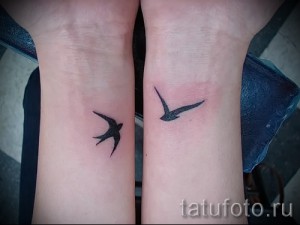 Фото двух маленьких татуировок ласточек на запястьях. Черно-белый рисунок, минимализм.