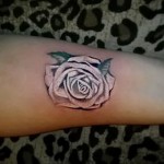 Фото тату: маленькая роза на запястье, стиль blackwork, четкие линии, минималистичный рисунок татуировки, женская рука.