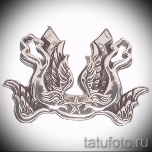 Фото тату с изображением двух серебряных кораблей, стилизованных под старинные парусники, с морской звездой между ними. Детализированный рисунок татуировки.