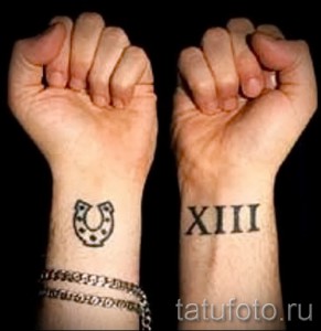 Фотография двух минималистичных татуировок на запястьях: черная подкова и римские цифры XIII. Простой и лаконичный дизайн.