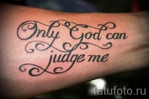 Фото тату на предплечье с надписью 'Only God can judge me' выполненной красивым шрифтом с декоративными элементами. Смысловая и выразительная татуировка.