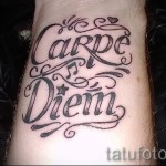 Фото тату на запястье с надписью 'Carpe Diem' выполненной красивым каллиграфическим шрифтом. Элегантный и вдохновляющий рисунок татуировки.