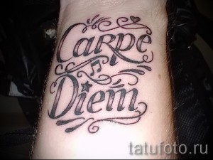 Фото тату на запястье с надписью 'Carpe Diem' выполненной красивым каллиграфическим шрифтом. Элегантный и вдохновляющий рисунок татуировки.