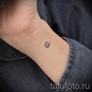 Фото тату на запястье: маленькая буква "G", выполненная в черном цвете. Простой и элегантный рисунок татуировки.