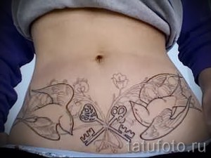 Фото тату на животе: черно-коричневый рисунок с изображением двух птиц и ключей. Детализированный эскиз татуировки.