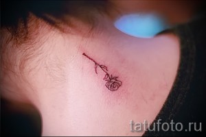 Фото тату: маленькая, изящная татуировка розы, выполненная тонкими линиями, расположена за ухом девушки. Идеальный эскиз тату для любителей минимализма.