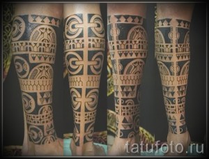 Фото тату: сложный полинезийский орнамент, покрывающий всю голень. Черные узоры с геометрическими формами и спиралями.