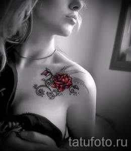 Фото тату: изящная красная роза с тонкими линиями и детальной проработкой на ключице девушки. Нежный и романтичный эскиз татуировки.