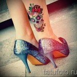Фото тату: Цветная татуировка в стиле sugar skull с розами и узорами на женской лодыжке. Яркие цвета и детализированный рисунок.