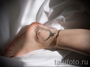 Фото татуировки: полумесяц с цветами на лодыжке. Изящный и женственный рисунок татуировки в черно-серых тонах.