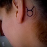 Фото готовой тату знак зодиака телец - за ухом у молодой девушки