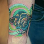 Фото готовой тату знак зодиака телец - зелено-желтая татуировка на запястье у мужчины