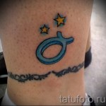 Фото готовой тату знак зодиака телец - синий символ и желтые звезды в рисунке внизу ноги