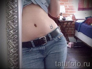 Фото тату: маленькая черно-белая татуировка символа Тельца на животе. Минималистичный дизайн, тонкие линии, изящное расположение.