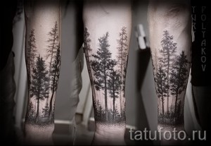 Черно-серая татуировка на голени, изображающая густой лес с высокими деревьями. Рисунок татуировки выполнен в реалистичной манере с использованием точечной техники.