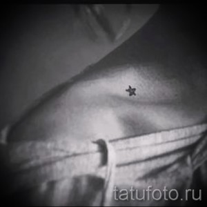 Фото минималистичной татуировки на шее: маленькая черная звезда, выполненная тонкими линиями.