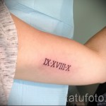 Фото тату: небольшая татуировка с римскими цифрами 'IX XVIII X' на внутренней стороне предплечья. Черный цвет, минималистичный дизайн.